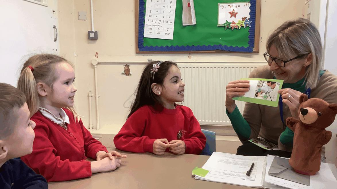 Teacher showing a flash card to children in a NELI group session